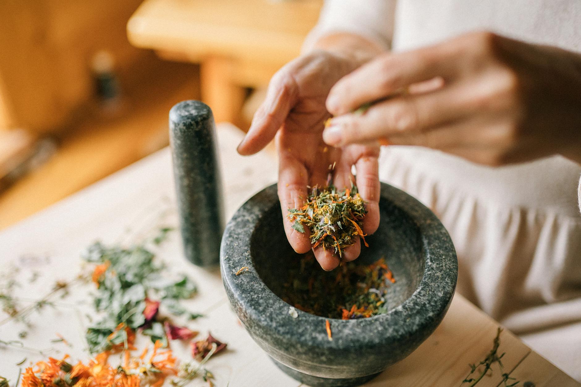 close up of woman preparing herbs in pounder