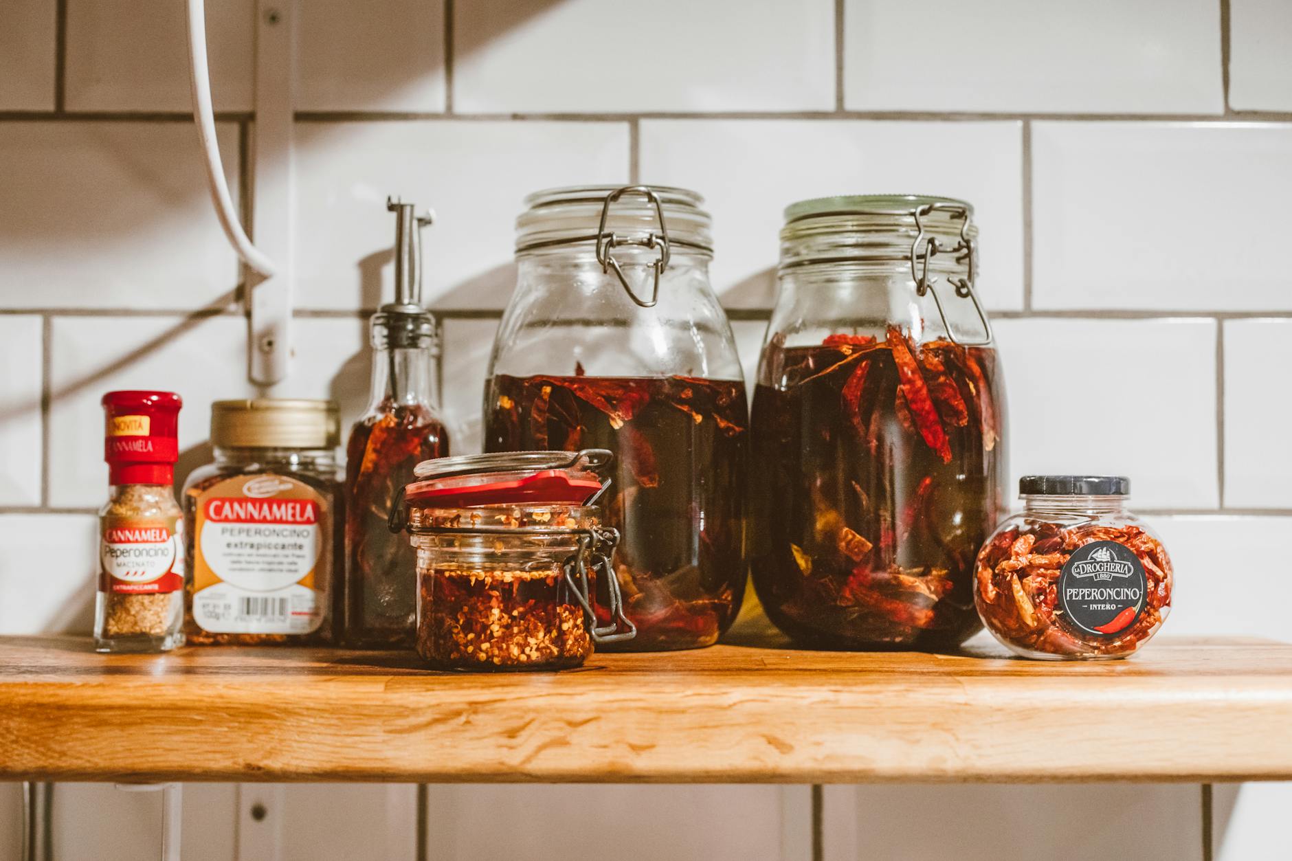 clear glass jars of condiments on brown wooden shelf